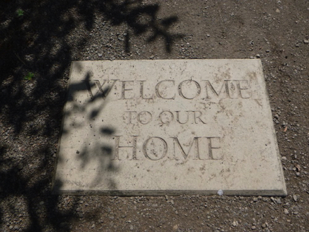 Concrete stepping stone at trail entrance says ‘Welcome to our home’ –  may have a lip